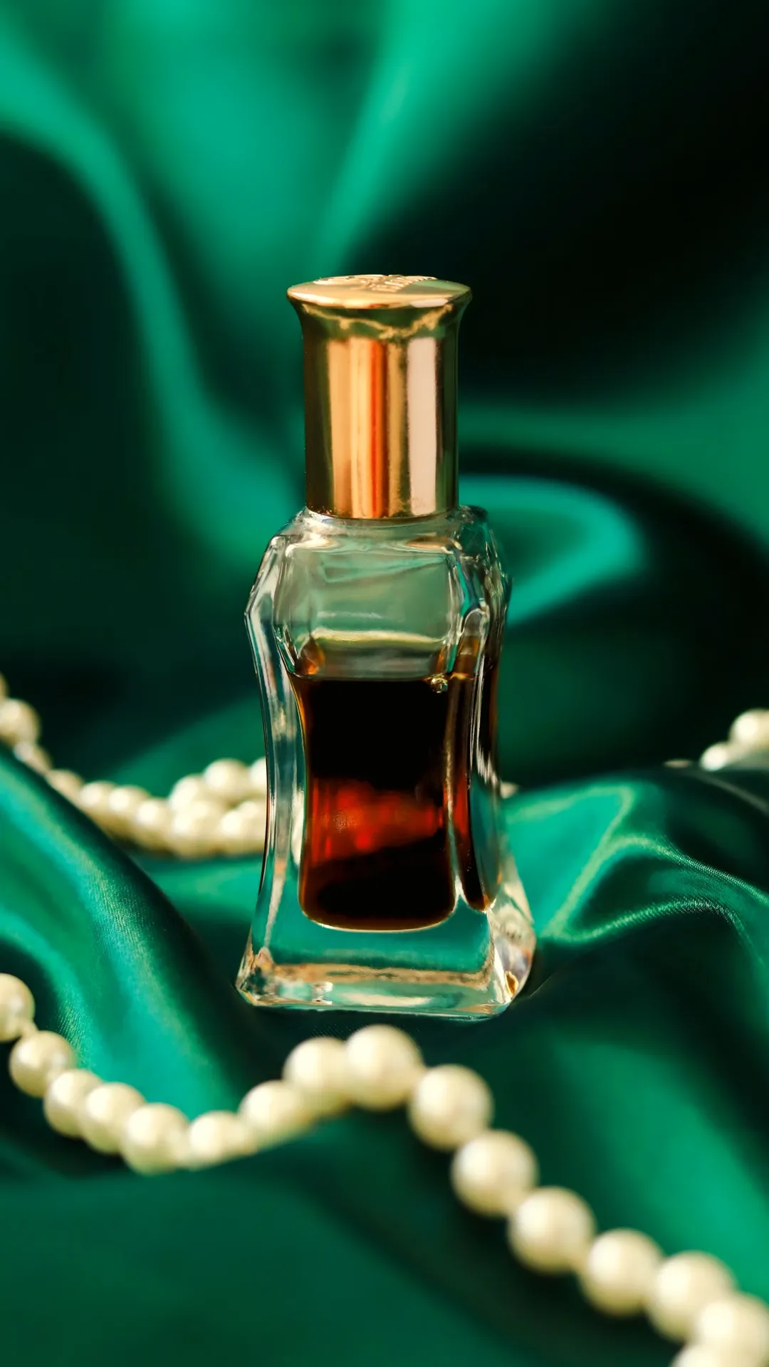Minimal attar bottle on emerald silk with pearls