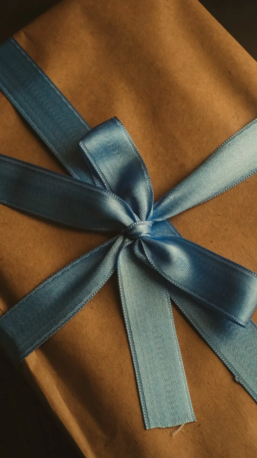 Kraft-wrapped gift box with a dusty-blue satin bow